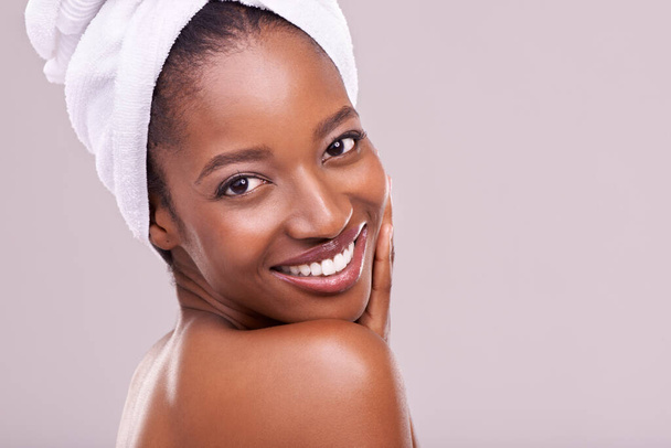 Ręcznik do włosów, portret i szczęśliwa czarna kobieta w studio do pielęgnacji skóry, wellness lub pielęgnacji ciała na fioletowym tle. Piękno, czyszczenie lub ręce na twarzy afrykańskiej modelki z kosmetykiem, połyskiem lub blaskiem. - Zdjęcie, obraz