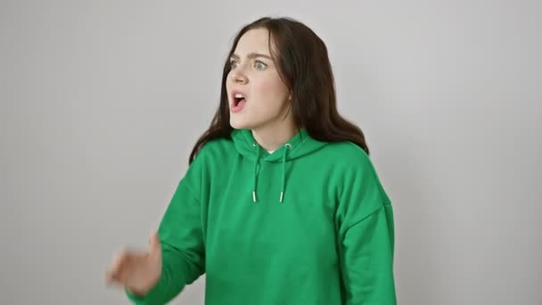 Frustrovaná mladá žena v mikině křičí! s hlasitým křikem, s rukou na ústech, vysílající zuřivý vzkaz. izolované na čistě bílém pozadí - Záběry, video