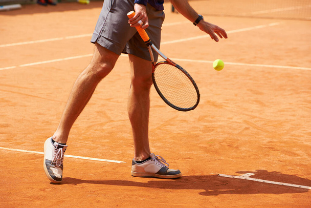 Τένις, το δικαστήριο και τα πόδια του προσώπου εξωτερική στην αρχή της άσκησης της προπόνηση στον ανταγωνισμό. Αθλητής, σερβιτόρος και sneakers της προπόνησης παίκτη με μπάλα σε πήλινο γήπεδο στον αθλητισμό, το παιχνίδι και τη δράση στο fitness. - Φωτογραφία, εικόνα