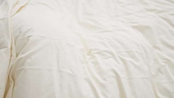Een jonge Kaukasische vrouw slaapt rustig in een gezellige overdekte slaapkamer, gewikkeld in zacht wit beddengoed. - Video