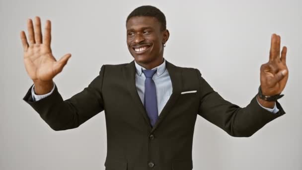 Onnellinen afrikkalainen amerikkalainen mies puvussa seisoo, hymyilee, ja itsevarmasti näyttää numero kahdeksan sormillaan osoittaessaan ylöspäin. eristetty valkoisella pohjalla. - Materiaali, video