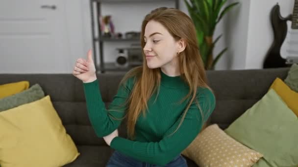 Csodálatos fiatal szőke nő, aki otthon érzi magát, büszkén sportos pulóvert visel, és nagyot mosolyog, miközben egy-oké jelet ad, felemeli a hüvelykujját oldalra.! - Felvétel, videó