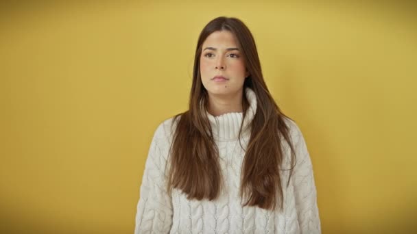 Simmering surprise! stunning young hispanic woman in yellow background, mouth agape in amazement, pointing ahead. isolated cutout of her great discover, wearing sweater, oblivious to the observer! - Footage, Video