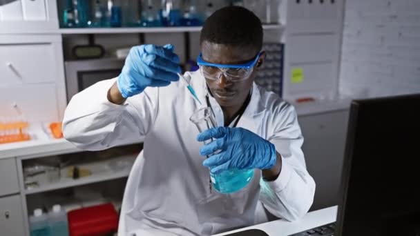 Hombre científico africano analizando líquido azul en laboratorio - Metraje, vídeo