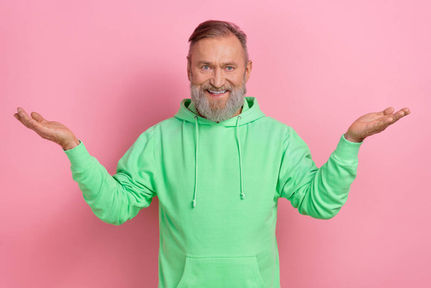 Photo of cheerful positive man wear green sweatshirt comparing arms empty space isolated pink color background. - Valokuva, kuva
