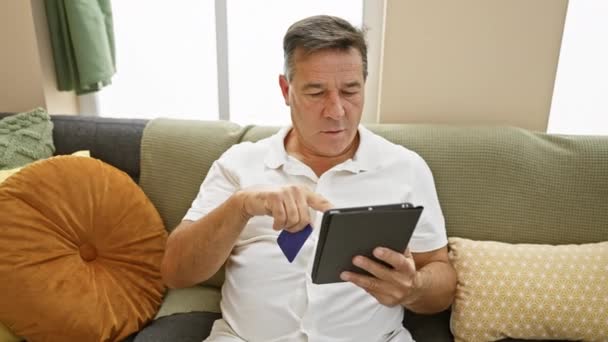 Homme mûr utilisant tablette et carte de crédit pour les achats en ligne à la maison - Séquence, vidéo