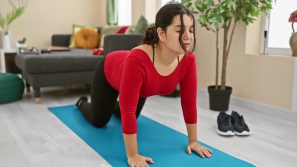 Hispanische Frau übt auf Yogamatte im Wohnzimmer und stellt Fitness, Wellness und modernen Lebensstil dar. - Filmmaterial, Video