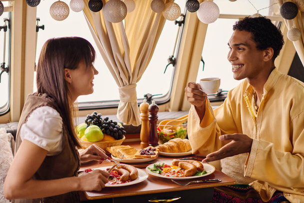 Um casal interracial desfrutando de um delicioso almoço em sua van campista. - Foto, Imagem