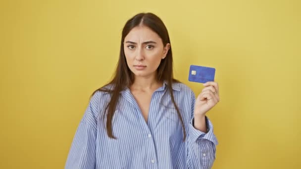 Merész arcú gyönyörű fiatal spanyol nő kezében hitelkártya, teszi stop jel kézzel. A komoly arckifejezése magabiztosságot sugall a védelemben. izolált sárga háttér hozzáteszi dráma. - Felvétel, videó