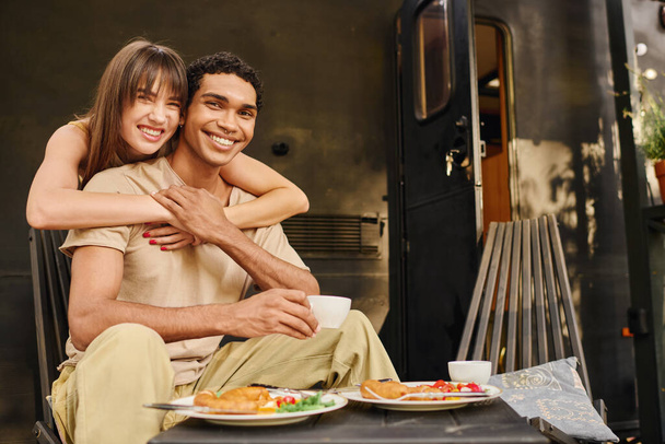 Mężczyzna i kobieta cieszą się spokojną chwilą na ławce przed vanem, mocząc się w scenerii. - Zdjęcie, obraz