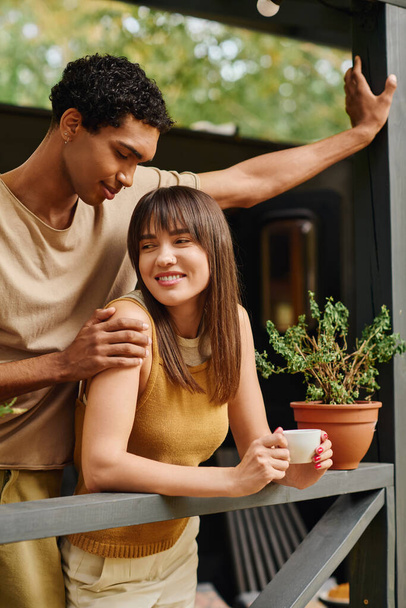 Un homme et une femme se tiennent ensemble sur un balcon, profitant d'un moment romantique. - Photo, image