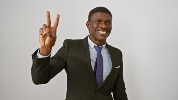 Веселий афроамериканський чоловік у костюмі впевнено стоїть, показуючи знак "номер два" пальцями, вказуючи, посміхаючись. ідеально ізольовані на білому тлі. - Кадри, відео