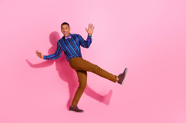 Teljes hosszúságú fotó a jó hangulat izgatott srác öltözött csíkos ing szórakozás diszkó üres tér elszigetelt rózsaszín háttér. - Fotó, kép