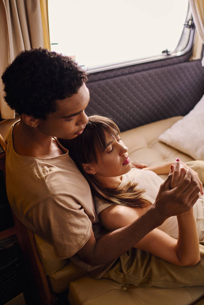 Een man en een vrouw zitten dicht bij elkaar op een bed, delen een moment van intimiteit en verbondenheid in een gezellige omgeving. - Foto, afbeelding