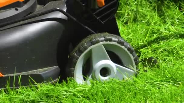 Bir banliyö evinde, yemyeşil çimenler elektrikli çim biçme makinesi kullanılarak titizlikle biçilir, iyi manikürlü ve davetkar bir dış mekan yaratır.. - Video, Çekim