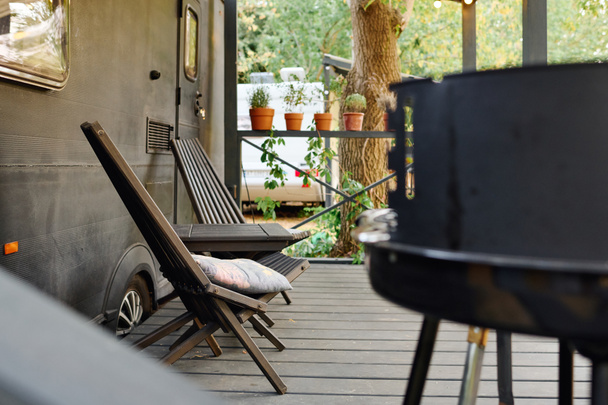 deck with a camper van, grill, and chairs, a romantic getaway in nature. - Photo, Image