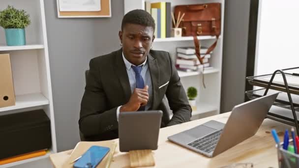 Jóképű fekete öltönyös férfi dolgozik laptop és tabletta modern irodai belső - Felvétel, videó