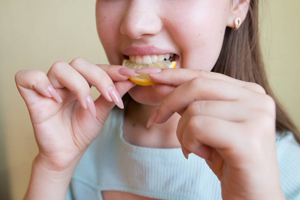 young beautiful girl eating lemon, close-up, crop photo. - Фото, изображение