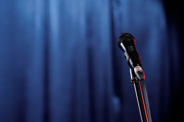 Mikrofon az állványon, felkészítve komikus vagy résztvevő előadására a kék színpad függönyeivel szemben - Fotó, kép
