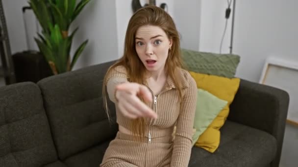 Blonde youngster, pointing an angry gesture at you through the camera inside her home, wearing a sweater. furious, displeased, and terribly frustrated. - Footage, Video