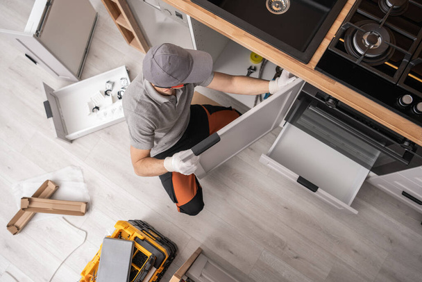 Professionele keukenkastmaker die meubels in een appartement installeert - Foto, afbeelding