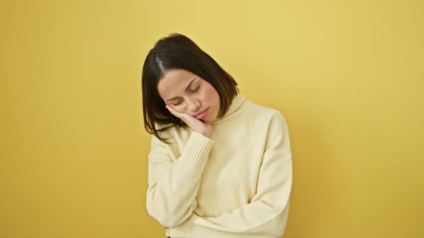 Depressieve jonge Spaanse vrouw, er moe uitziend, denkend aan haar problemen, verveelde haar mooie gezicht bedekt met verdriet, droeg een trui, gekruiste armen, staande tegen geïsoleerde gele muur - Video
