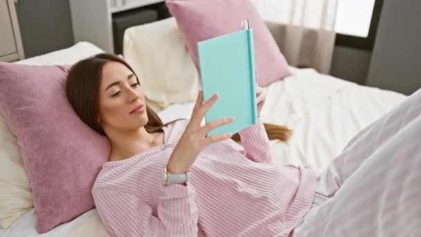 Nainen lukee kirjaa makuuhuoneessa yllään pyjama, ilmaista vapaa-aikaa ja mukavuutta. - Materiaali, video