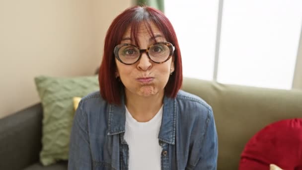 Orta yaşlı İspanyol bir kadının evde çılgınca bir ifade için yanaklarını şişirdiği komik bir sahne. Tişört giyip, neşeyle ağzını şişiriyor ve komik bir yüz ifadesi takınıyor.. - Video, Çekim