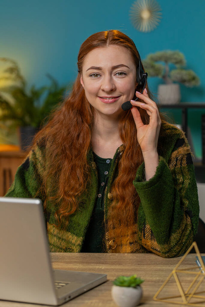 Business woman wearing headset, freelance worker, call center or support service operator helpline, talking with client or colleague communication support. Smiling girl sitting at home office desk - Photo, Image