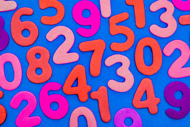 Mixed coloured numbers on a blue background. - Photo, Image