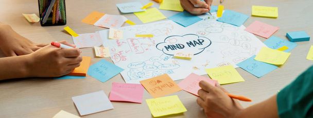 Profesjonalna grupa startupowa dzieli się kreatywnym pomysłem marketingowym za pomocą mapy umysłu. Młodzi wykwalifikowani biznesmeni burzą mózgów biznes plan podczas pisania lepkich notatek. Skup się na ręku. Zbliżenie. Różnorodność. - Zdjęcie, obraz