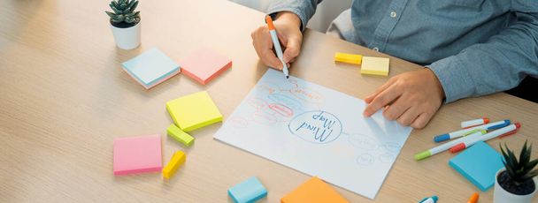 Skilled businessman brainstorms marketing ideas using mind maps. Successful male startup leader drafts financial plan on table with sticky notes scatter around. Closeup. Focus on hand.Variegated. - Photo, Image