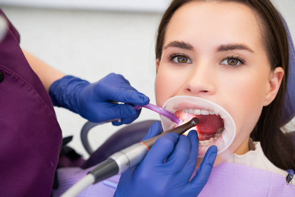 Молодая женщина проходит лечение кариеса в стоматологической клинике - Фото, изображение