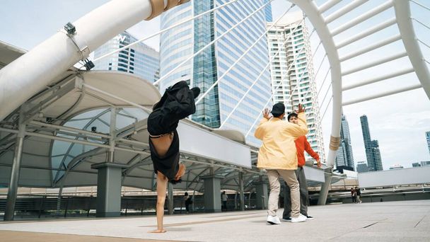 Egy csoport profi boldog utcai táncos fel, míg ázsiai hipster végre b fiú tánc a városi városban körül az emberek alacsony szögű kamera. Break tánc koncepció. Kültéri sport 2024. Élénk.. - Fotó, kép