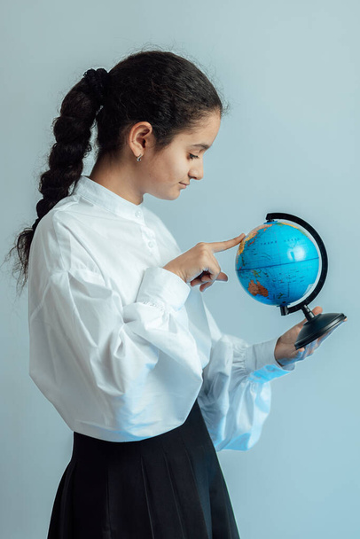 Retrato de estudio de una niña sosteniendo el globo terráqueo y explorando el mundo - Foto, Imagen