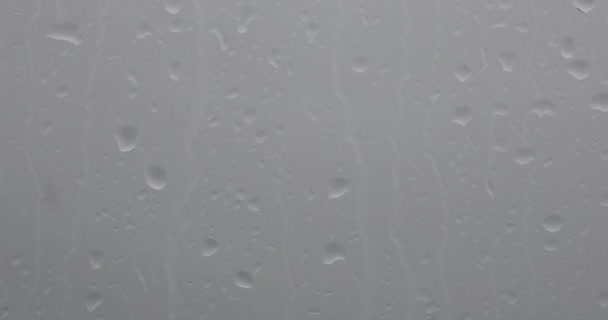 Esőcseppek az ablakon, homályos háttérrel. - Felvétel, videó