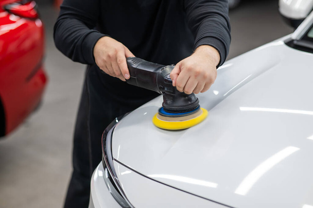 Process of polishing white car hood surface using orbital polishing machine - Valokuva, kuva