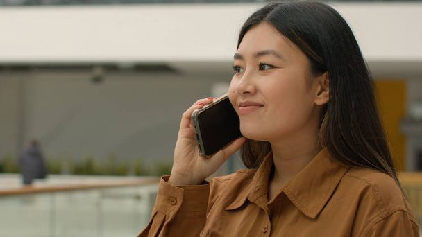 Ασιάτισσα επιχειρηματίας χαμογελώντας Κινέζα Γιαπωνέζα επιχειρηματίας γυναίκα επιχειρηματίας ευτυχισμένη Κορεάτισσα επιχειρηματίας μιλώντας κινητό τηλέφωνο απάντηση κλήση μιλάμε smartphone σε εσωτερικούς χώρους φιλική κουβέντα στο γραφείο - Φωτογραφία, εικόνα