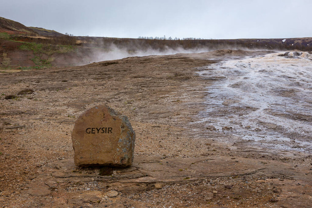 Il Grande Geysir nella zona geotermica in Islanda, piscina di sorgenti termali geyser fumante con cartello informativo in pietra "Geysir". - Foto, immagini