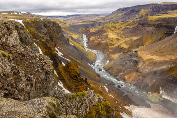 Fossardalur vallei landschap met verticale kliffen bedekt met gras en mos, gletsjer Fossa rivier stroomt hieronder, uitzicht vanaf Haifoss waterval, IJsland. - Foto, afbeelding