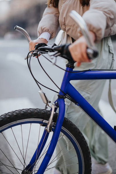 Частковий вид на жінку, яка насолоджується їздою на велосипеді в місті, з крупним планом на синій велосипед. - Фото, зображення
