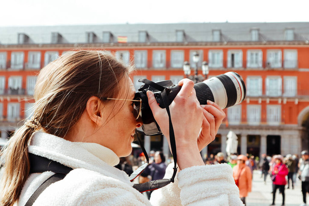 Madrid, Espagne. 27 février 2024 Une touriste photographiant une Plaza Mayor visitant la capitale espagnole. Photographe voyageur Vieux bâtiment rouge façade - Photo, image