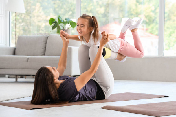 Boldog anya a kislányával otthon edz. - Fotó, kép