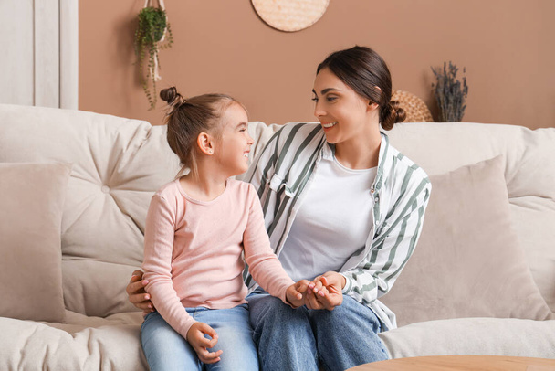 Щаслива мати зі своєю маленькою донькою сидить на дивані у вітальні - Фото, зображення