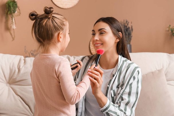 Happy little girl and her mother with brushes doing makeup at home - Photo, Image