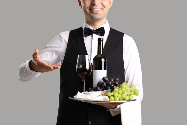 Молодий сомельєр з вином і закусками на сірому фоні, крупним планом - Фото, зображення
