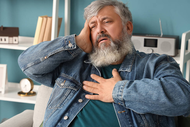 Portrait of sad senior man holding heart at home, closeup - Valokuva, kuva