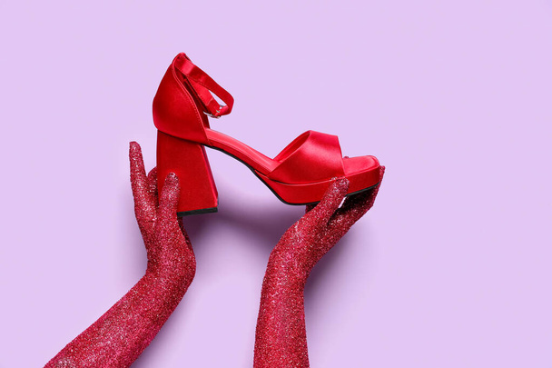 Naisten kädet peitetty glitter ja tyylikäs korkeakorkoiset kenkä lila tausta - Valokuva, kuva