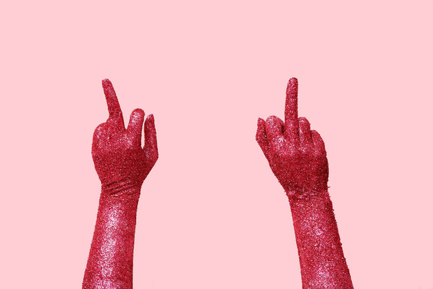 Mujer con las manos pintadas mostrando los dedos medios sobre fondo rosa, primer plano - Foto, Imagen