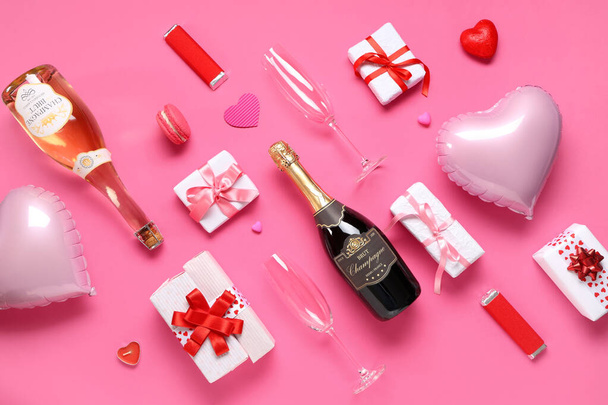 Botellas de champán con copas, cajas de regalo y decoración sobre fondo rosa. Celebración de San Valentín - Foto, imagen